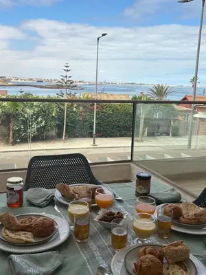 a table with plates of food and a view of the ocean at Luxury apartment with sea view and 2 pools Sablettes in Mohammedia