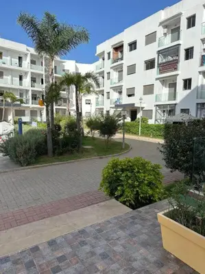 a large apartment building with palm trees and a courtyard at Hébergement idéal pour conjuguer tourisme, affaires et télétravail in Mohammedia