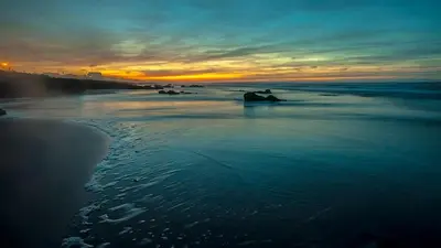 a view of the beach at sunset with the ocean at Hébergement idéal pour conjuguer tourisme, affaires et télétravail in Mohammedia