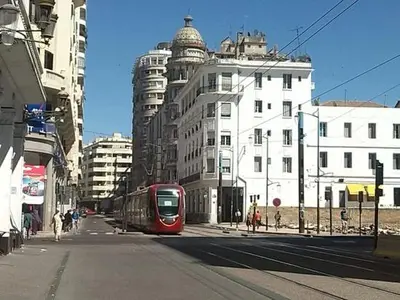 a red train on a city street with buildings at Terrace & View of Casablanca Port in Casablanca