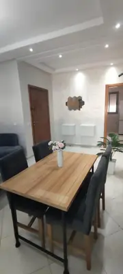 a dining room table with chairs and a wooden table at Résidence Sable Dor in Mohammedia