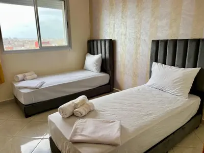 a bedroom with two beds and a window at Urban Comfort Casablanca - 3BR Family Apartment in Casablanca