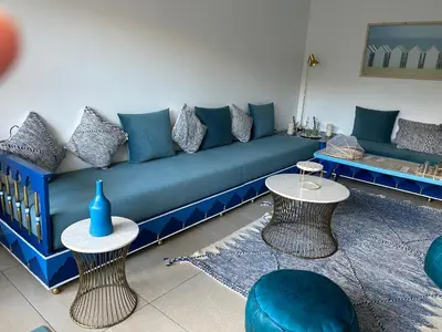 a living room with a blue couch and two tables at The Blue Beach apartment- Residence Skhirat Beach2 in Skhirat
