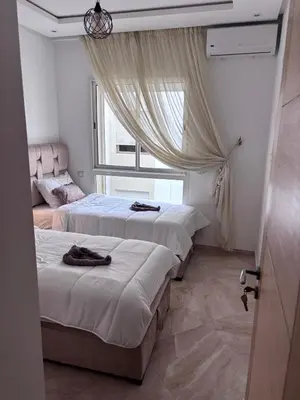 a room with three beds and a window at Shems Bouznika Residence Central & Cozy 2 Bedroom Apartment with Pool Bouznika in Bouznika