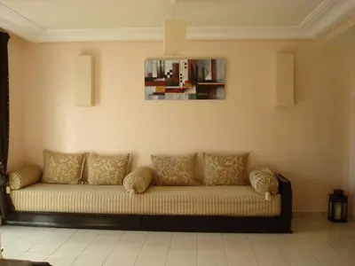 a couch in a living room with a painting on the wall at Appart face à la mer Garden Beach Sidi Rahal plage in Sidi Rahal