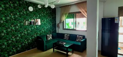 a living room with a couch and a green wall at Mansouria Appartement avec Piscine à proximité de la Plage in Mansouria