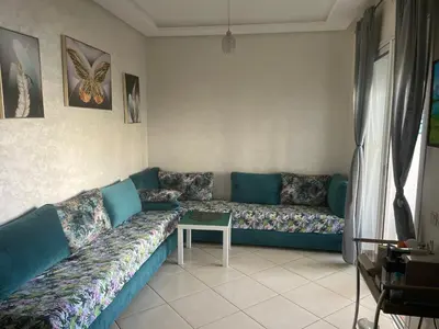 a living room with a blue couch and a table at Garden beach 2 in Sidi Rahal