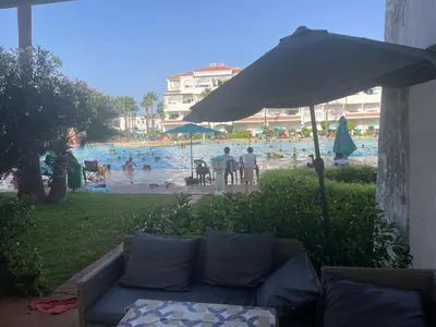 a couch under an umbrella next to a swimming pool at Garden beach 2 in Sidi Rahal