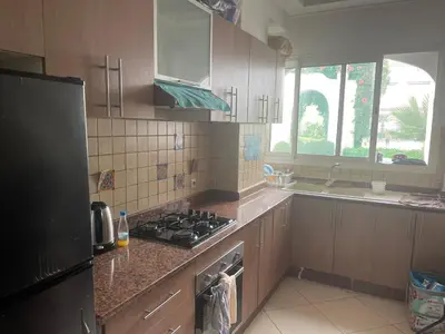a kitchen with wooden cabinets and a stove top oven at Garden beach 2 in Sidi Rahal