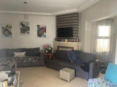 a living room with a couch and a television at Garden beach 2 in Sidi Rahal
