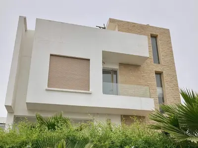 a white building with a window on the side of it at Belle et spacieuse villa avec piscine privée in Casablanca