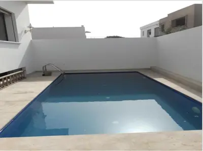 a blue swimming pool on the side of a building at Belle et spacieuse villa avec piscine privée in Casablanca