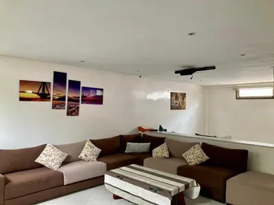 a living room with a couch and a table at Belle et spacieuse villa avec piscine privée in Casablanca