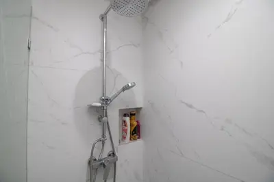 a shower in a bathroom with white marble walls at Modern Studio 5min CFC in Casablanca