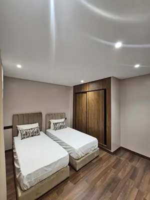two beds in a room with wooden floors at Luxury Apartment 5min CFC in Anfa