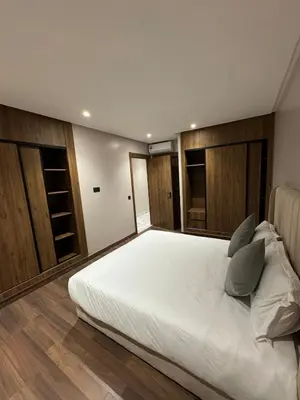 a bedroom with a large white bed with wooden cabinets at Luxury Apartment 5min CFC in Anfa