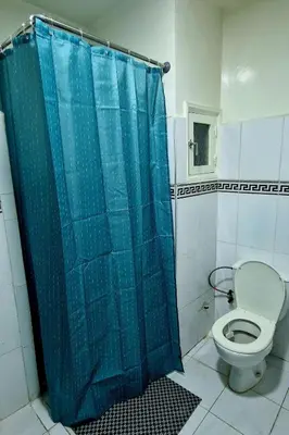 a bathroom with a toilet with a blue shower curtain at Parisien Studio in Rabat