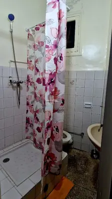 a bathroom with a shower with a floral shower curtain at Nice studio for nice people in Rabat