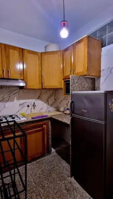 a kitchen with wooden cabinets and a black refrigerator at Greeny Studio in Rabat