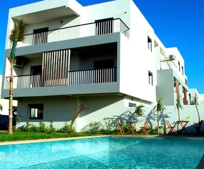 a building with a swimming pool in front of a building at Appartement pieds sur mer in Sidi Rahal