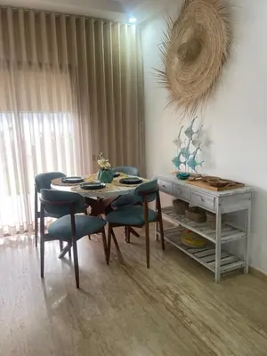 a dining room with a table and chairs and a table and a table at Appartement pieds sur mer in Sidi Rahal