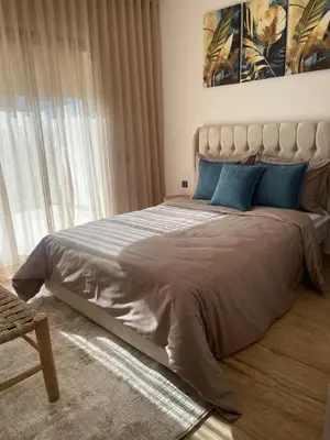 a bedroom with a large bed with blue pillows at Appartement pieds sur mer in Sidi Rahal