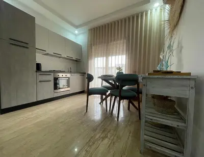 a kitchen with a table and chairs in a room at Appartement pieds sur mer in Sidi Rahal