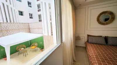 a room with a balcony with chairs and a bed at Cosy and central condo with terace steps to shore in Rabat