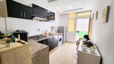 a kitchen with black and white appliances in a room at Cosy and central condo with terace steps to shore in Rabat