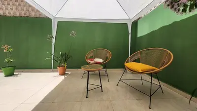two chairs with yellow cushions sitting next to a green wall at Cosy and central condo with terace steps to shore in Rabat