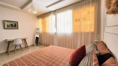 a bedroom with a bed and a desk and a window at Cosy and central condo with terace steps to shore in Rabat