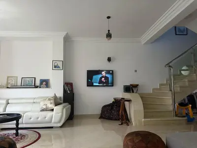 a living room with a couch and a tv on the wall at Maison ensoleillée à Skhirat, Piscine & Parking in Skhirat