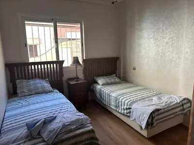 a bedroom with two beds and a window at Appartement A Darbouazza Tamaris 5min accès a la plage in Tamaris