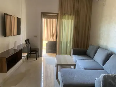 a living room with a couch and a table at Appartement neuf avec piscine in Bouznika