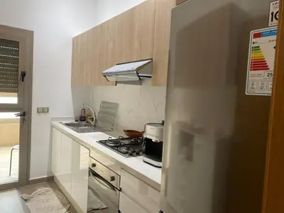 a kitchen with a stove and a refrigerator at Appartement neuf avec piscine in Bouznika