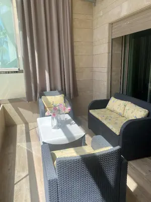 a living room with two chairs and a table and a couch at Appartement neuf avec piscine in Bouznika