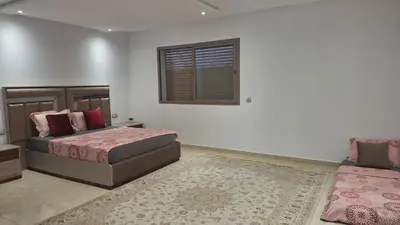 a bedroom with two beds and a window and a rug at Chambres au sein d'une villa in Rabat