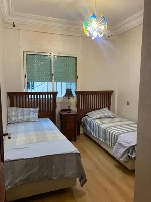 a bedroom with two beds and a chandelier at Très bel Appartement A Darbouazza Tamaris in Tamaris