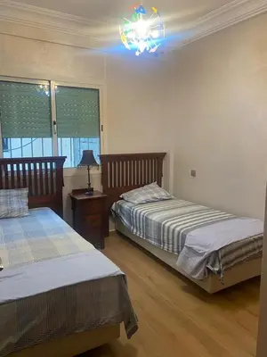 a bedroom with two beds and a table with a lamp at Très bel Appartement A Darbouazza Tamaris in Tamaris