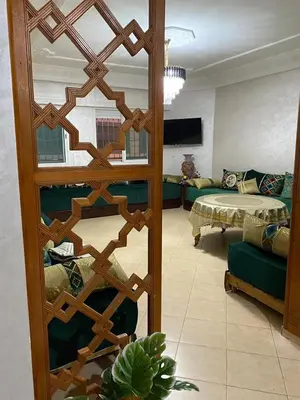a room with a living room with a bed and a mirror at Très bel Appartement A Darbouazza Tamaris in Tamaris