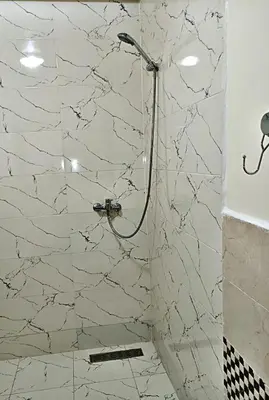 a bathroom with a shower with a white marble wall at Kridarek - Bel appartement avec piscine in Sidi Rahal