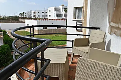 a balcony with chairs and a railing on a building at Kridarek - Bel appartement avec piscine in Sidi Rahal