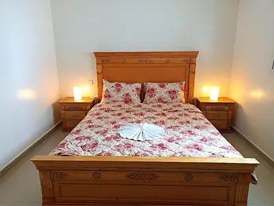a bedroom with a bed with two candles on two tables at Kridarek - Bel appartement avec piscine in Sidi Rahal