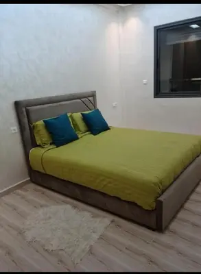 a bed with blue and yellow pillows in a room at Maison vacances à bouznika in Bouznika