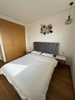 a bedroom with a large bed with white sheets at 2BR Prestigia Hay Riad in Rabat