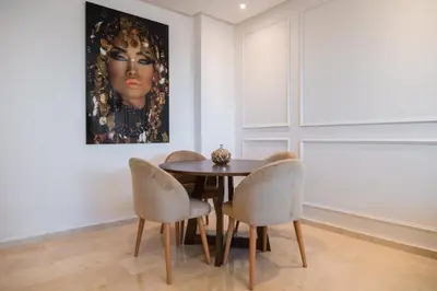 a dining room with a table and chairs and a painting at 2BR Prestigia Hay Riad in Rabat