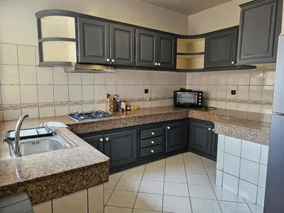 a kitchen with black cabinets and a sink at Maarif Central Stay in Maarif