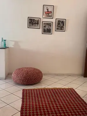 a room with a red ottoman and pictures on the wall at Maarif Central Stay 2 in Maarif