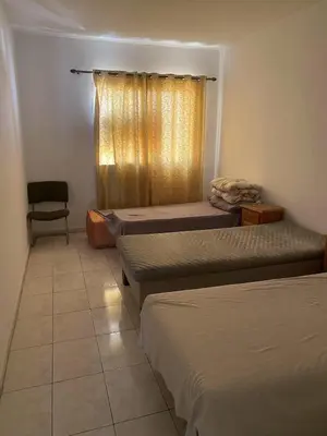a room with three beds and a chair and a window at Happy hostel in Casablanca
