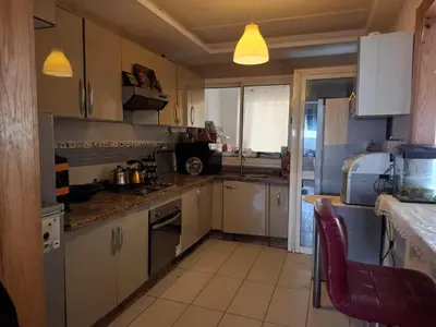 a kitchen with white cabinets and a red chair at Appart Coquette à Tamariss in Tamaris